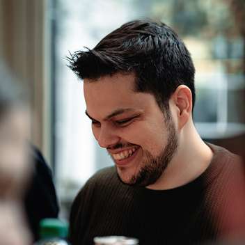 Amadeus sitzt lachend an seinem Arbeitsplatz im Coworking-Space.