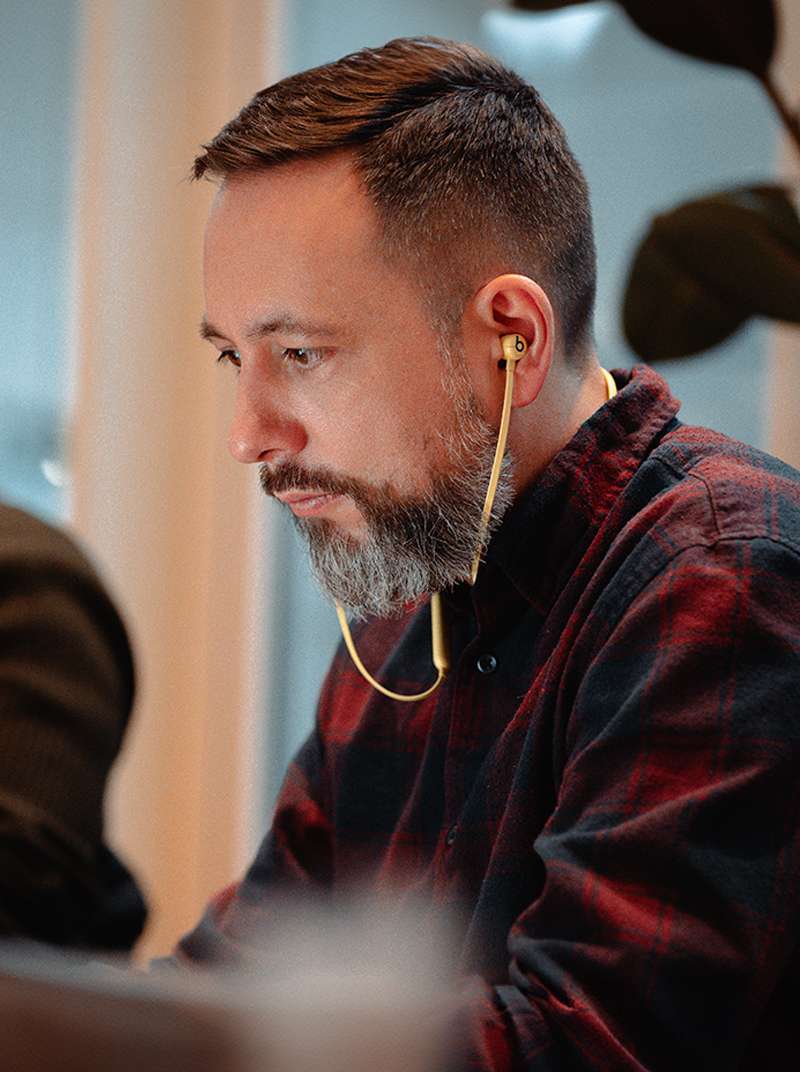 Arne arbeitet konzentriert mit Kopfhörern im Coworking-Space.