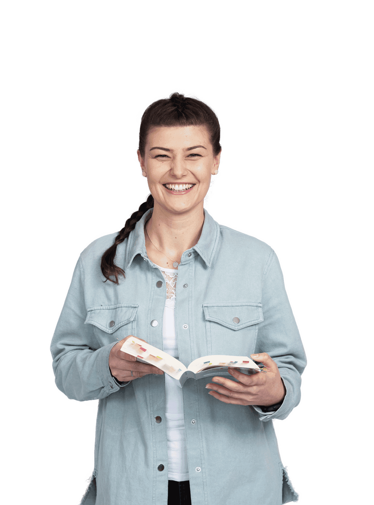 Eine Frau im offenen Jeanshemd steht vor transparentem Hintergrund, hält ein aufgeschlagenes Buch mit Markierungszetteln in den Händen und lacht.