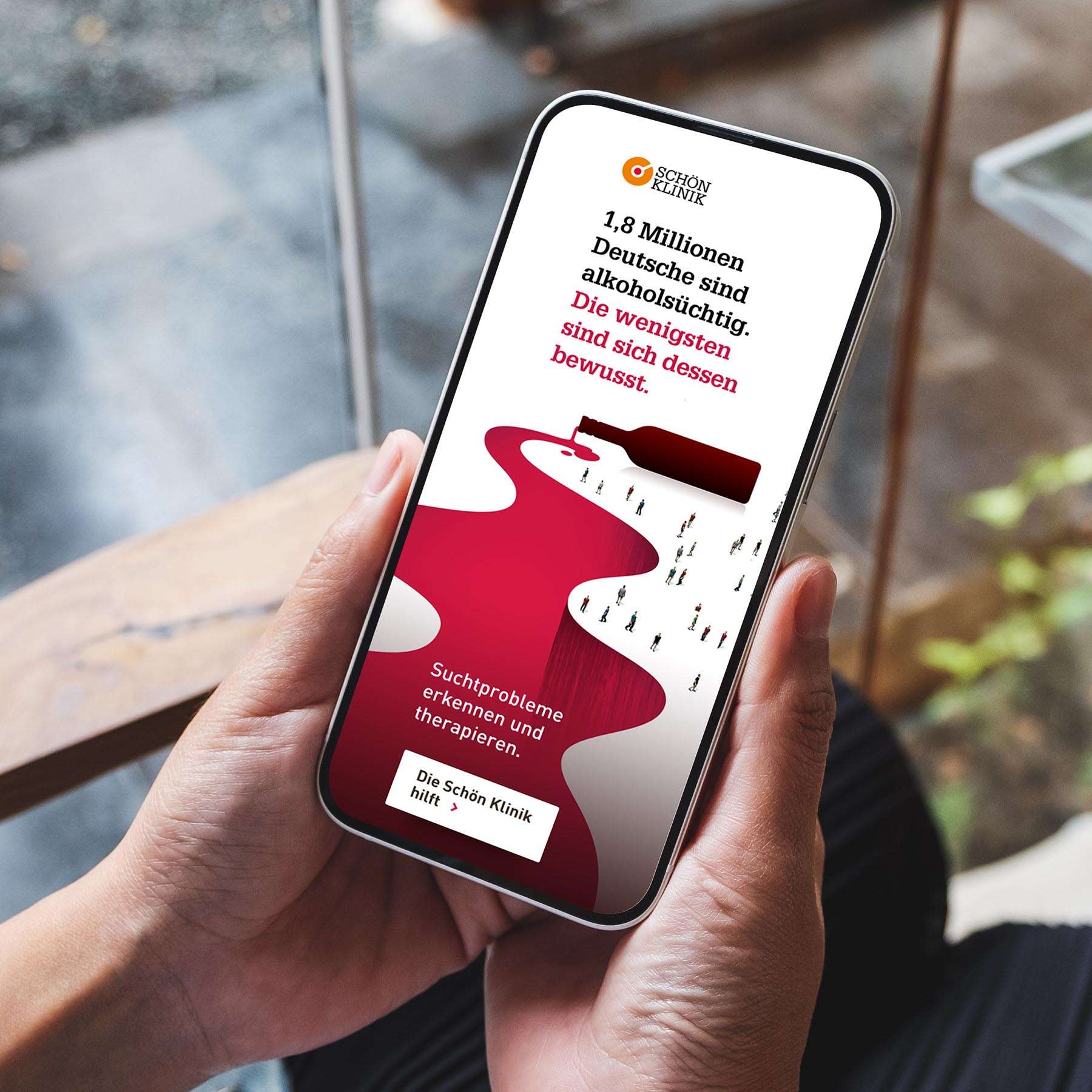 Zwei Hände halten ein Smartphone in der Hand, auf der eine Anzeige aus der Social Media Kampagne der Schön Klinik zum Thema Alkoholsucht zu sehen ist.